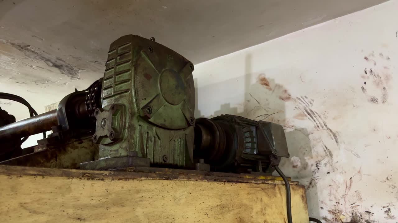 Close-up of industrial gearbox, electric motor and chain mounted on running conveyor