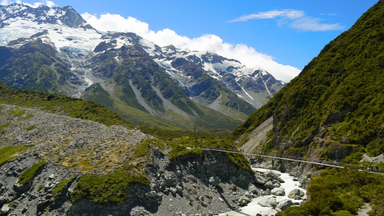 panorámica del turismo caminando por la pista del valle de hooker hacia los altos glaciares