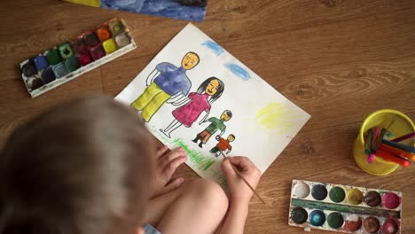 a child paints a drawing on the floor with watercolors. drawing depicting a family 04