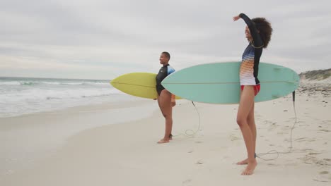 Fröhliche-Afroamerikanische-Freundinnen-Am-Strand-Mit-Surfbrettern-Und-Blick-Auf-Das-Meer