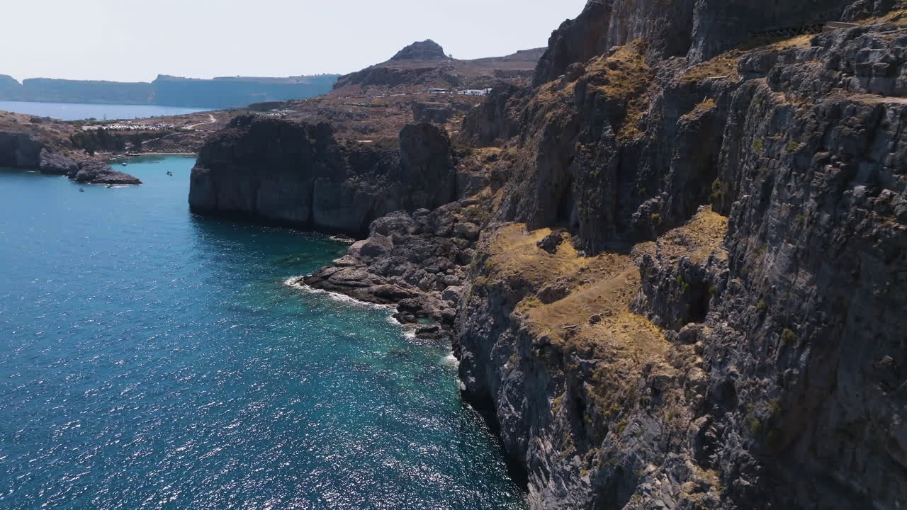Aerial view flying close to rocky cliffs on the coastline of Rhodes, sunny Greece