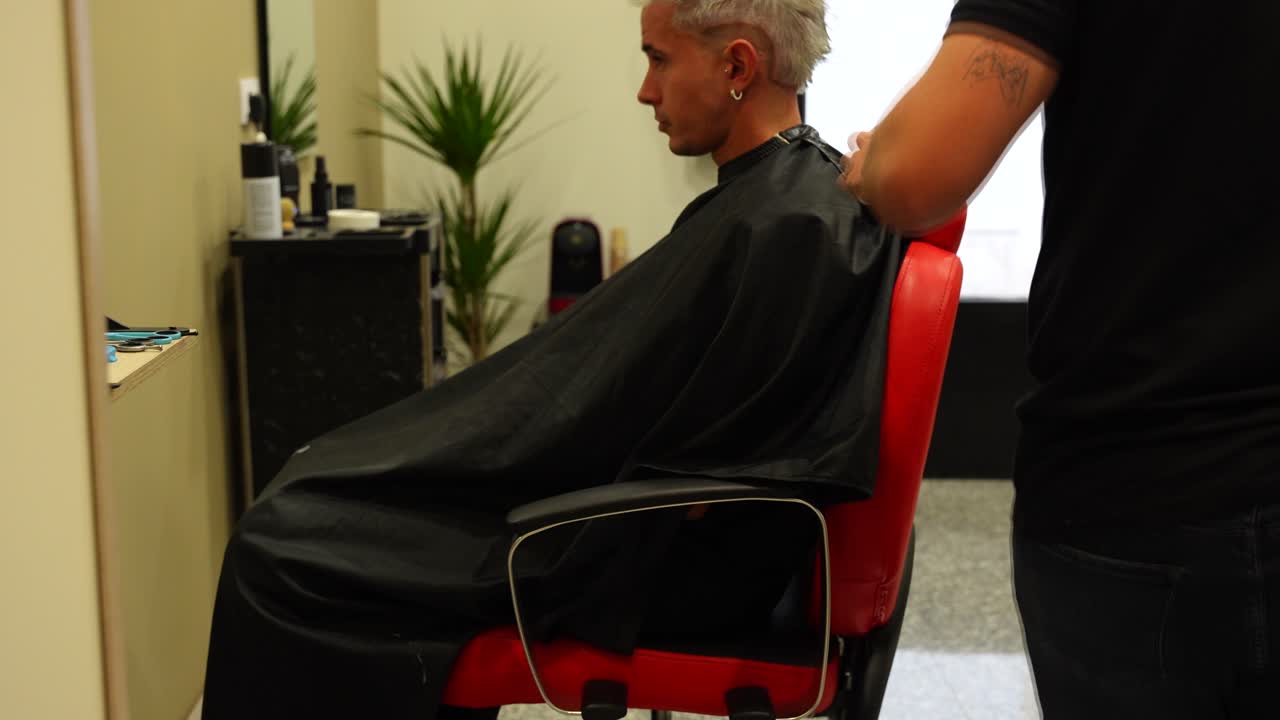 Frisøren tager en hårtørrer og begynder at tørre kundens hår i slowmotion