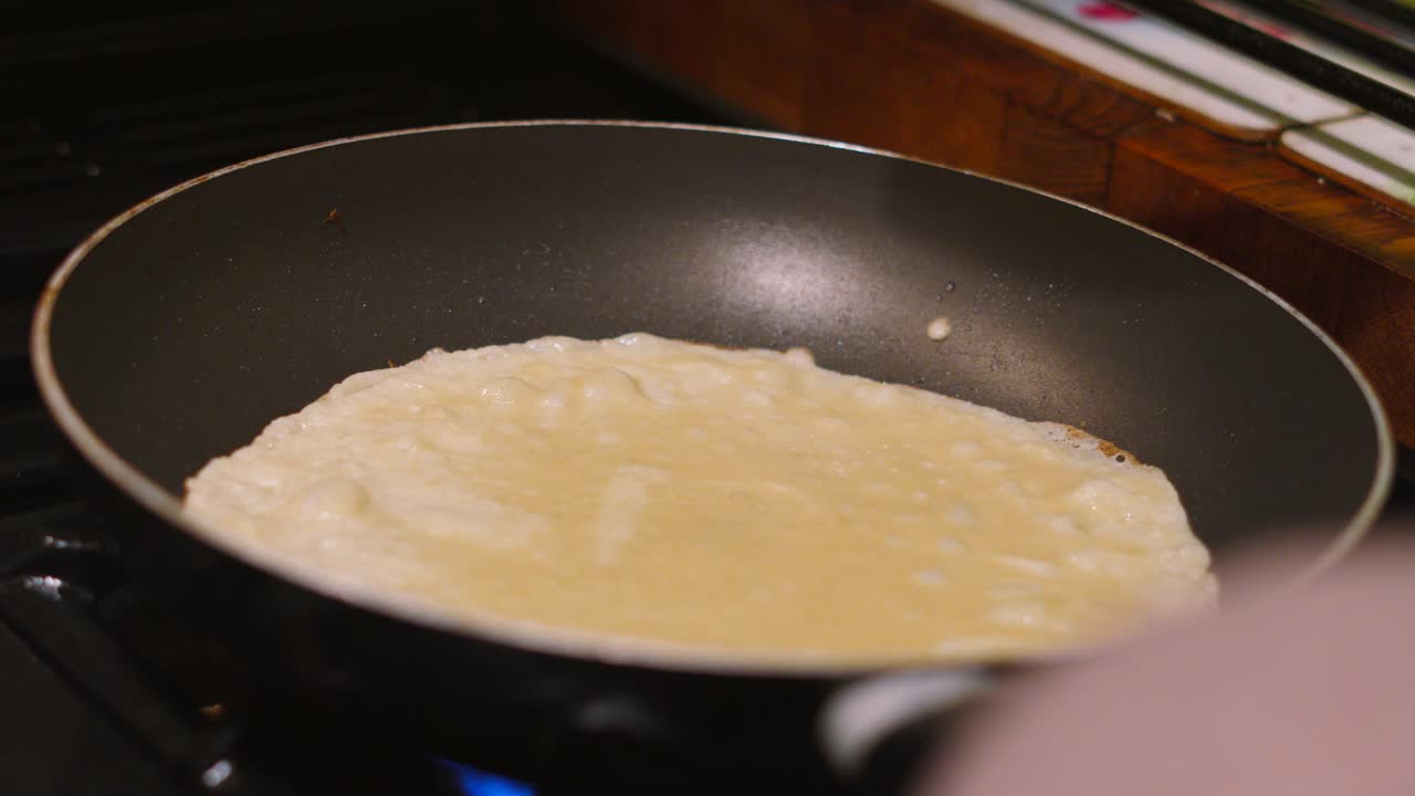 Pancake Being Cooked in Hot Frying Pan on Gas Kitchen Stove by Chef with Spatula. Traditional British Dessert or Breakfast. Cooking Food Photography.