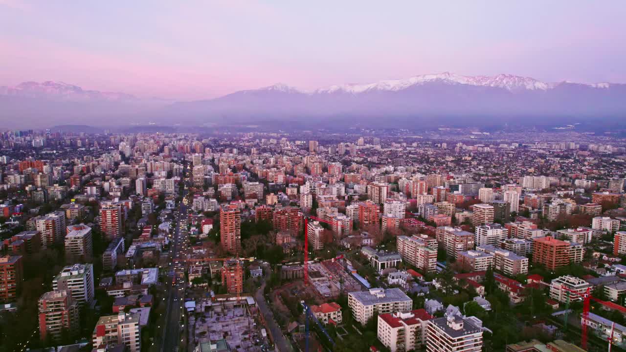 Aerial view establishing Santiago with the snowy mountain range in the background purple sunset Chile