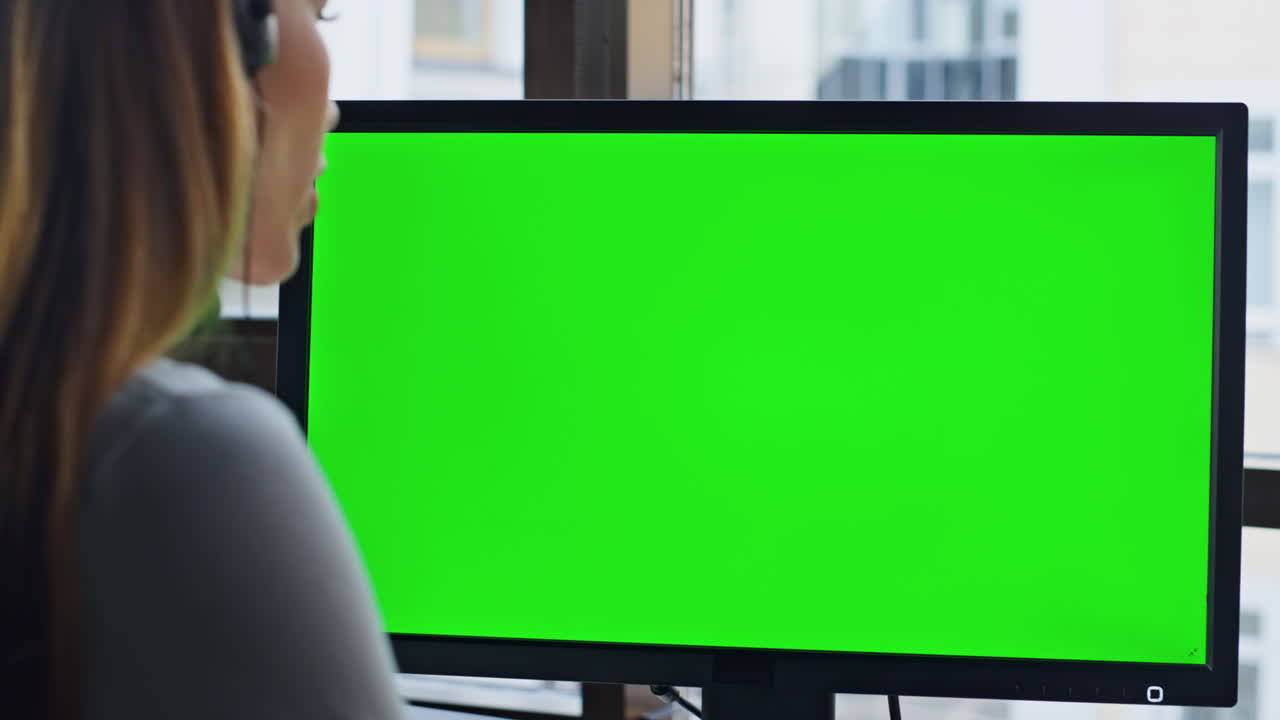 Nahaufnahme eines Firmenmitarbeiters, der an einem grünen Computer arbeitet. Büro mit Chroma-Key-Ausrüstung.