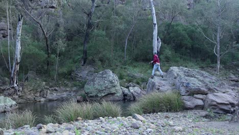 A-outdoors-man-casts-a-fishing-rod-from-a-rock-into-a-river-in-the-Victorian-highcountry
