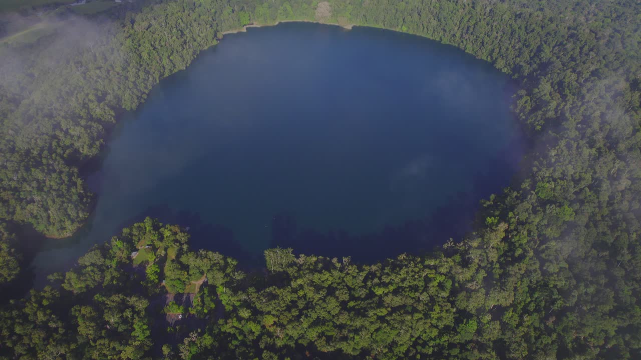 vista superior del lago eacham con aguas tranquilas y vegetación exuberante en la meseta de atherton, queensland, australia - disparo de drones