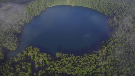 vista superior del lago eacham con aguas tranquilas y vegetación exuberante en la meseta de atherton, queensland, australia - disparo de drones