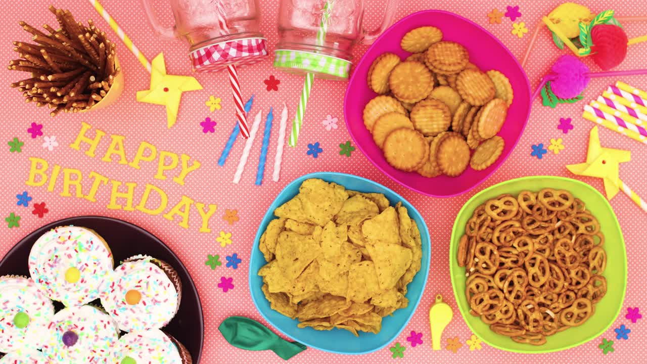 mesa para la fiesta con comida y decoraciones y feliz cumpleaños título en movimiento - stop motion