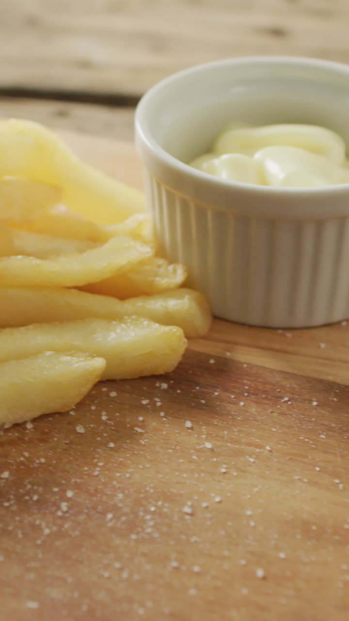Video di fish and chips con spicchio di limone e salsa su tagliere di legno, su tavolo rustico.