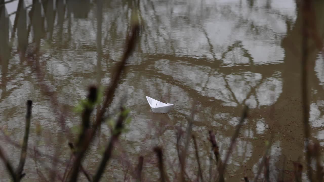 Small Paper Boat Floats On The Dirty Water Of Flood. handheld shot