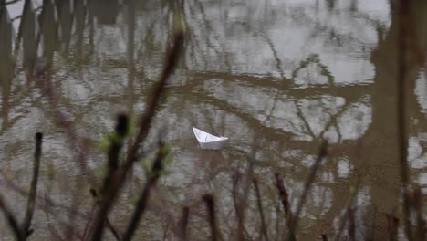 small paper boat floats on the dirty water of flood. handheld shot
