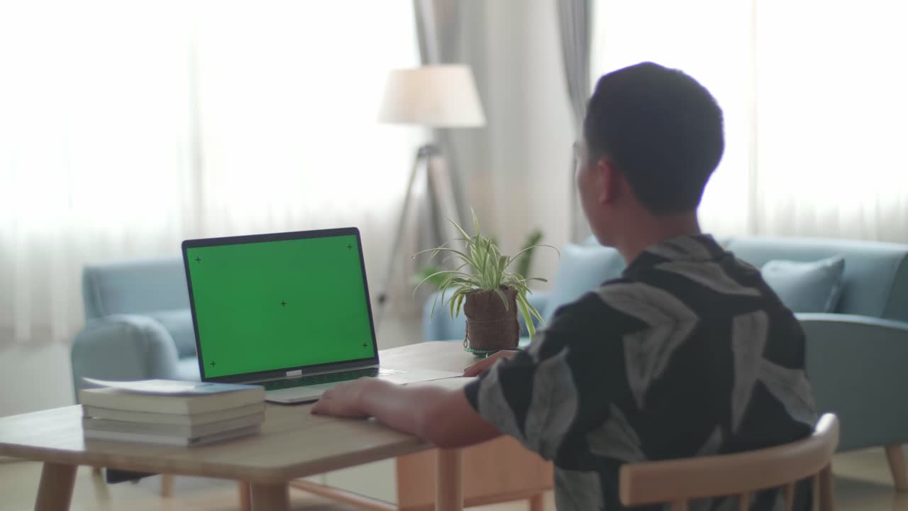 Asia Boy Sitting At His Desk Learning Online On A Laptop With Green Mock-Up Screen At Home, Raising Hand Distance Learning Online At Virtual Lesson Class At Home