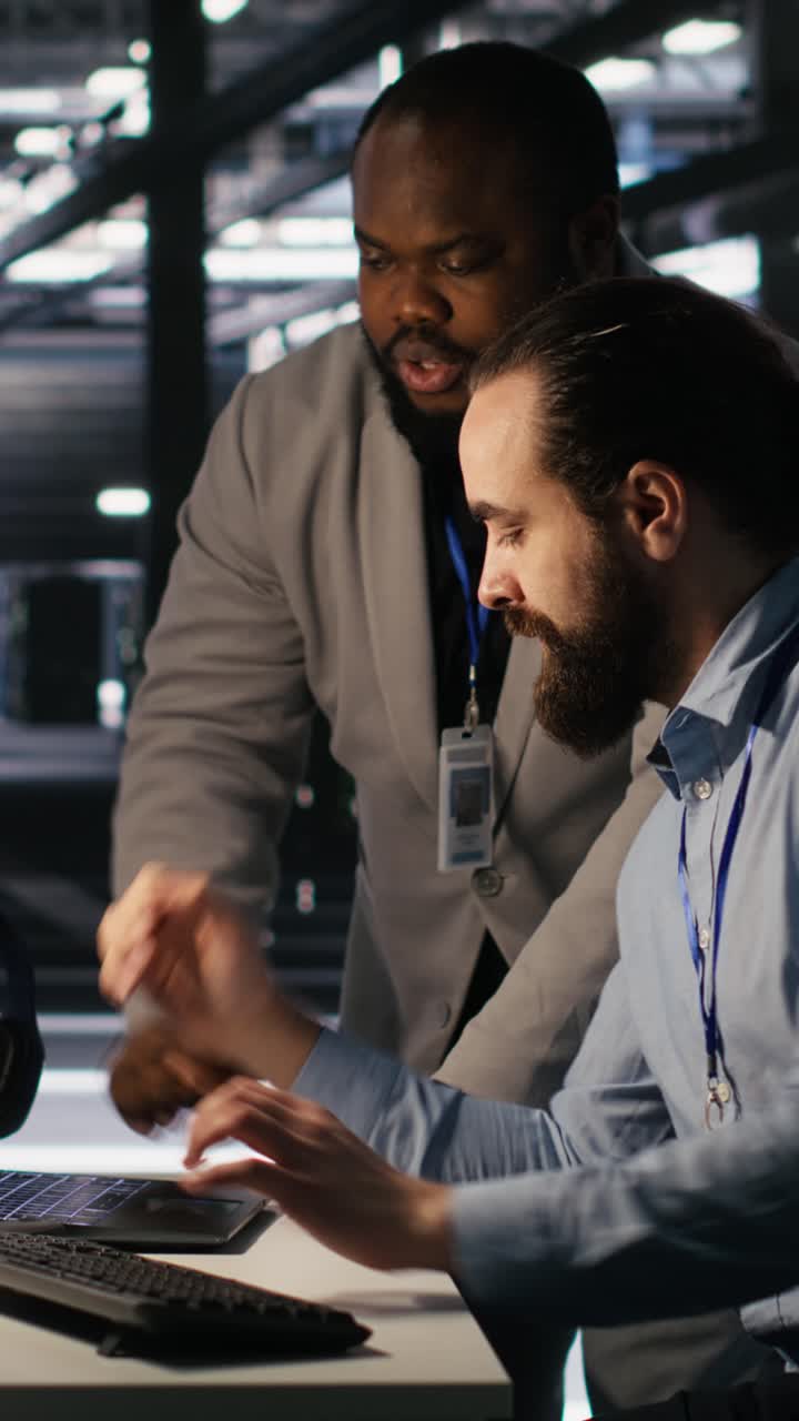 Vertical video Data center engineers use laptop, collaborating on doing AI software updates