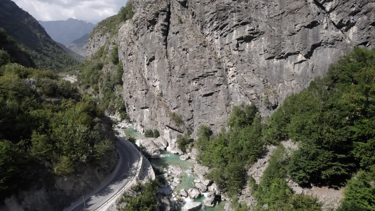 video con drone de descubrimiento de avioneta en grua ascendiendo sobre el rio valbone, comienza muy cerca del agua y termina arriba del cerro mostrando todo el rio al lado de la carretera