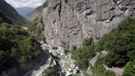 Video-Con-Drone-De-Descubrimiento-De-Avioneta-En-Grua-Ascendiendo-Sobre-El-Rio-Valbone,-Comienza-Muy-Cerca-Del-Agua-Y-Termina-Arriba-Del-Cerro-Mostrando-Todo-El-Rio-Al-Lado-De-La-Carretera