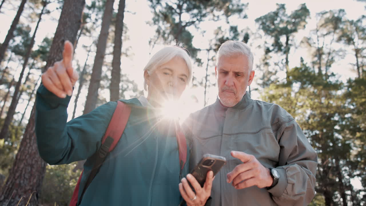 una pareja de ancianos haciendo senderismo y usando un teléfono.