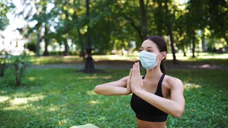 woman practicing yoga in a park during the pandemic wearing a mask