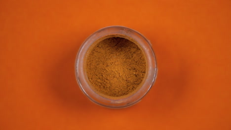 un vaso de polvo de pimienta naranja, en una superficie giratoria
