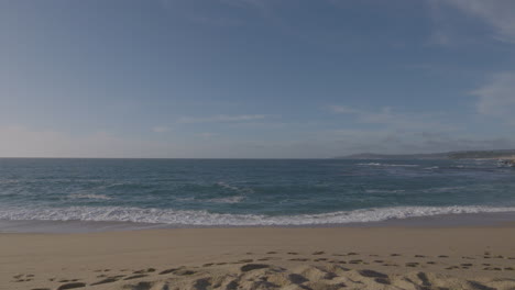 toma panorámica en cámara lenta de la playa y las olas en un día soleado en la playa estatal del puerto deportivo de la bahía de monterey de california
