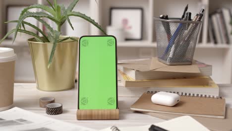 smartphone with green screen in cozy office interior