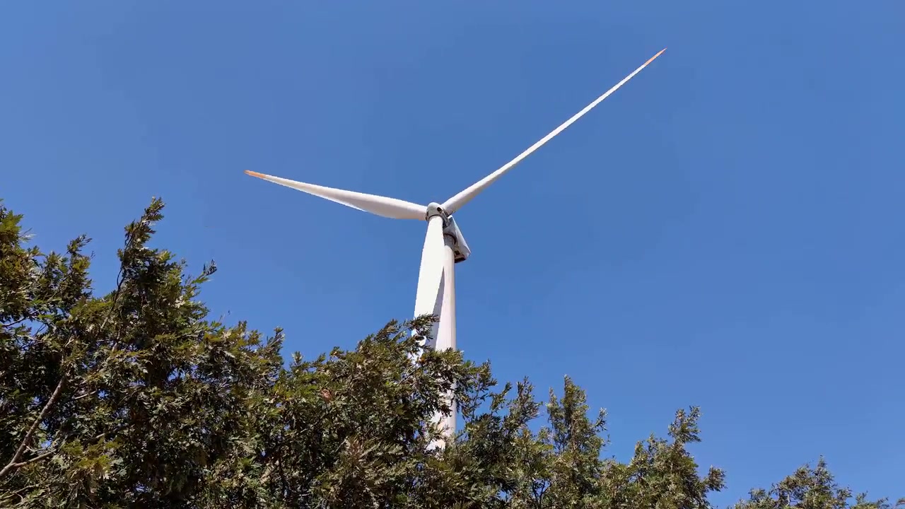 Stor vindmølle roterer mod en klar blå himmel