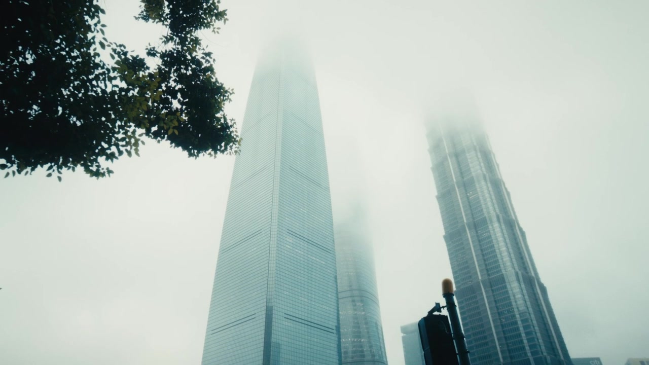 Inquadratura dal basso verso l'alto della Shanghai Tower, dello Shanghai World Financial Center e della Jin Mao Tower che si ergono in una fitta nebbia bianca invernale dal Lujiazui Central Green, Pudong, Shanghai.