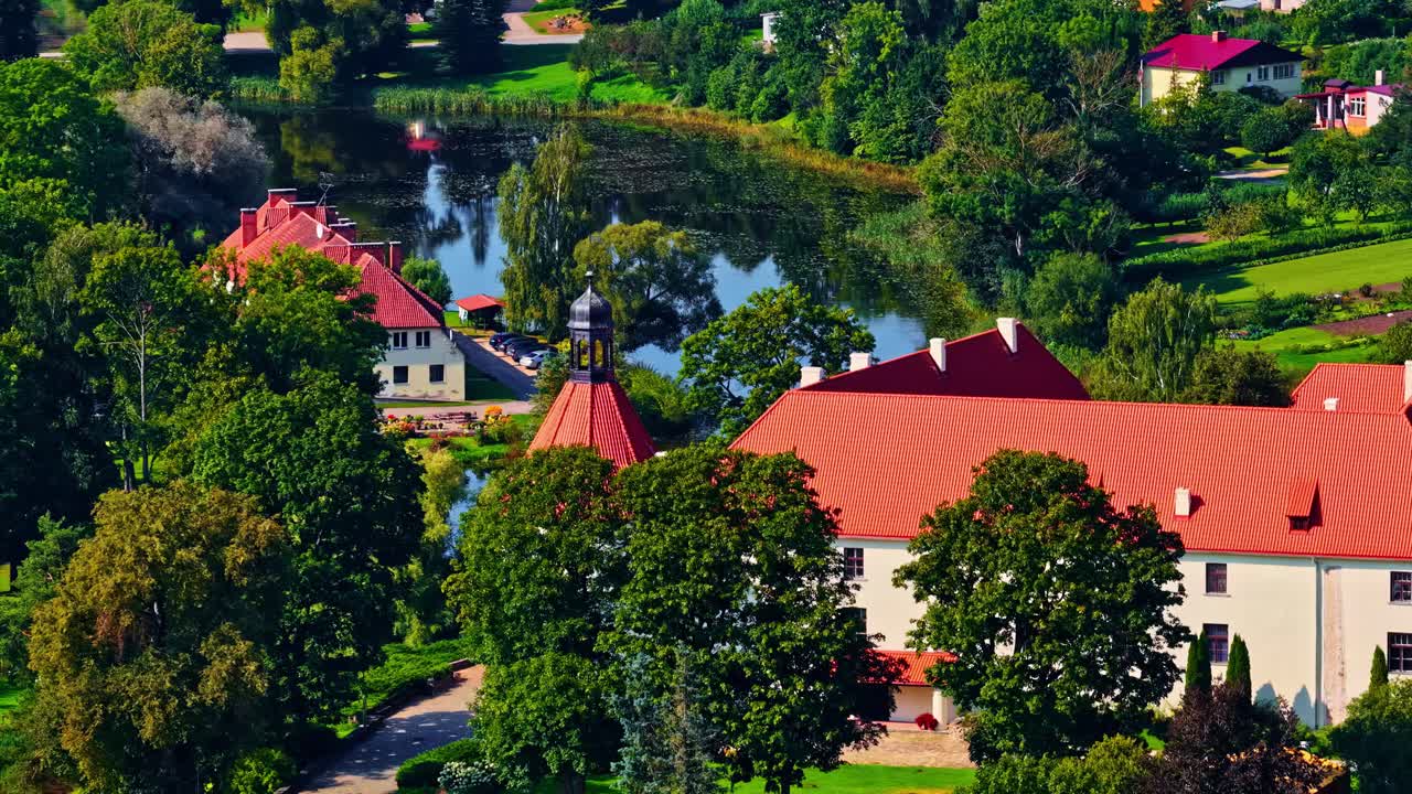 Veduta aerea del Castello di Jaunpils con edifici storici dal tetto rosso sotto il sole.