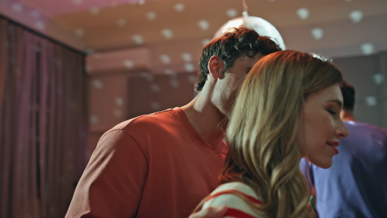 Relaxed couple enjoy disco party dancing with friends at night apartment closeup