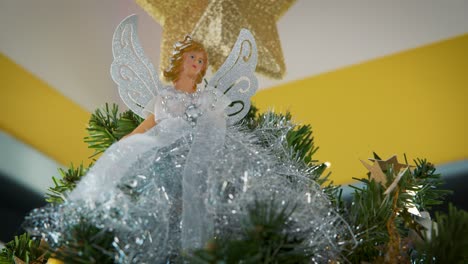 figura de ángel y decoración de estrella dorada en la parte superior del árbol de navidad