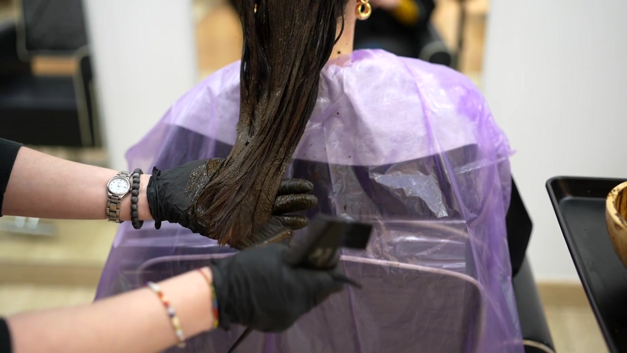 Parrucchiere che applica la tintura sui capelli di un cliente in salone