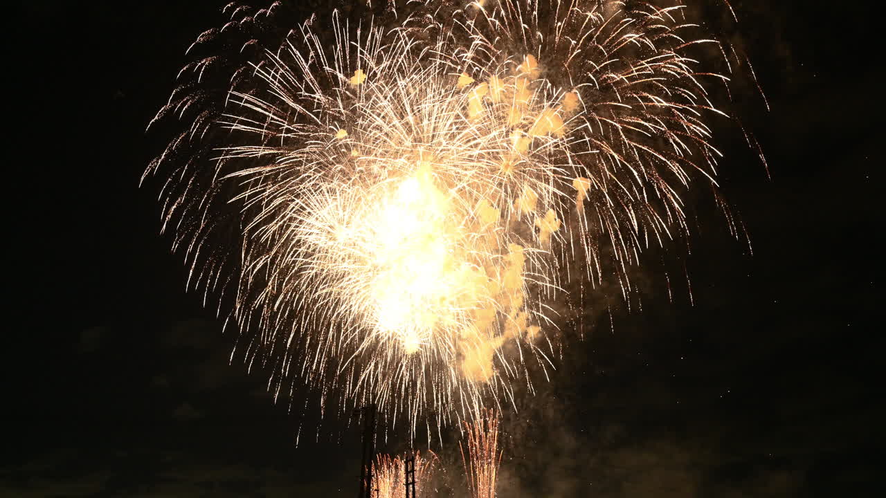 Brillanti fuochi d'artificio dorati che esplodono nel cielo notturno buio