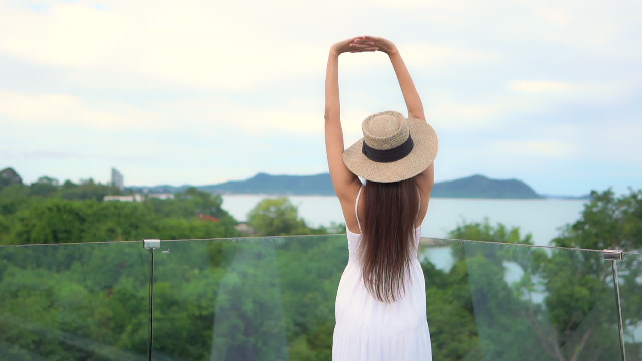 A young woman walks to the edge of resort pool barrier to enjoy the ocean view. copy space