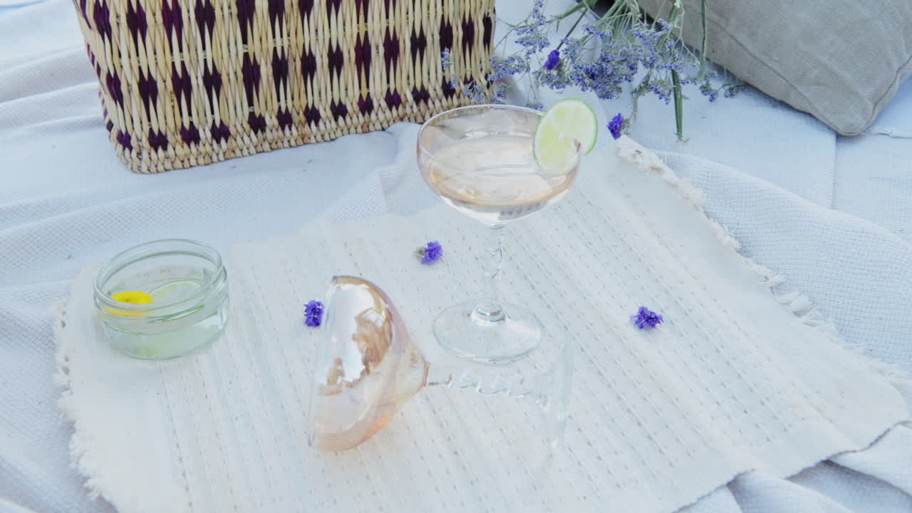 Placing A Cocktail With Lemon Slice on a picnic blanket for al fresco dining on holiday - flat lay close up