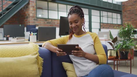 feliz mujer de negocios afroamericana usando tableta en la oficina