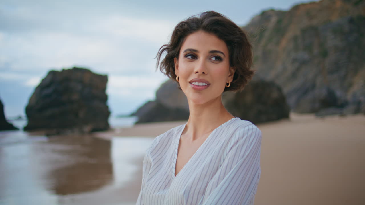 Primo piano di donna in spiaggia che chiude gli occhi in un abbraccio. Ragazza viaggiatrice che si gode la brezza marina.