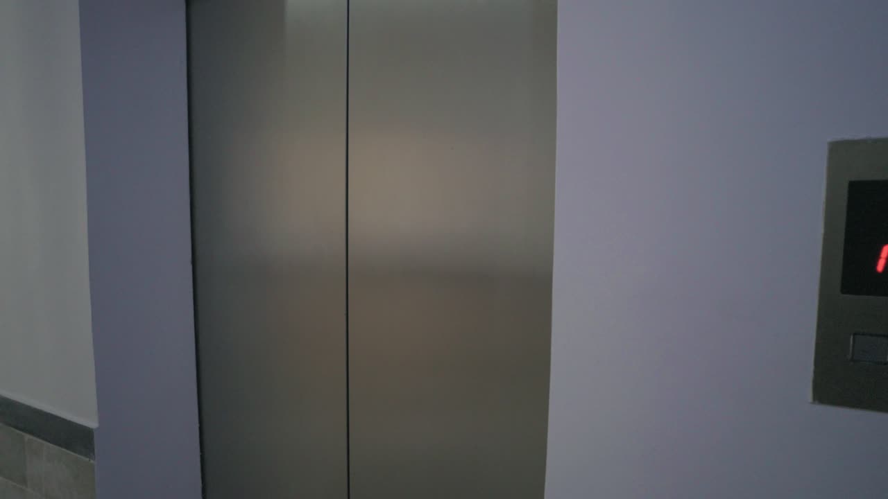 Elevator panel with floor indicator near a clean hospital hallway with bright light.