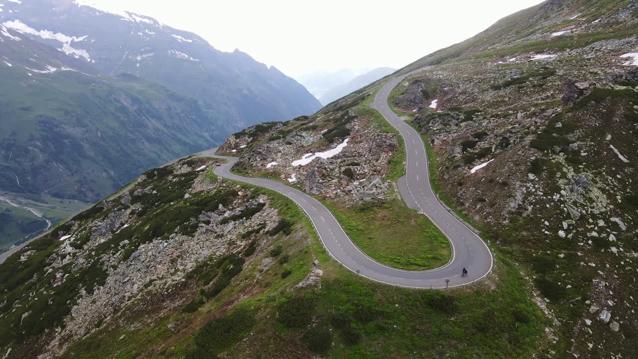 Static drone shot shows bikepacker climbing Grossglockner High Alpine Road
