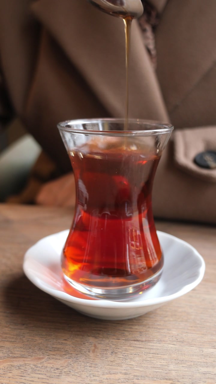 Hand Stirring Hot Tea in a Traditional Glass