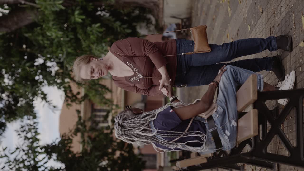 Two women greeting and interacting on a park bench