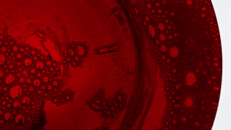 red sparkling liquor foaming wine glass closeup. fizzy drink moving inside glass