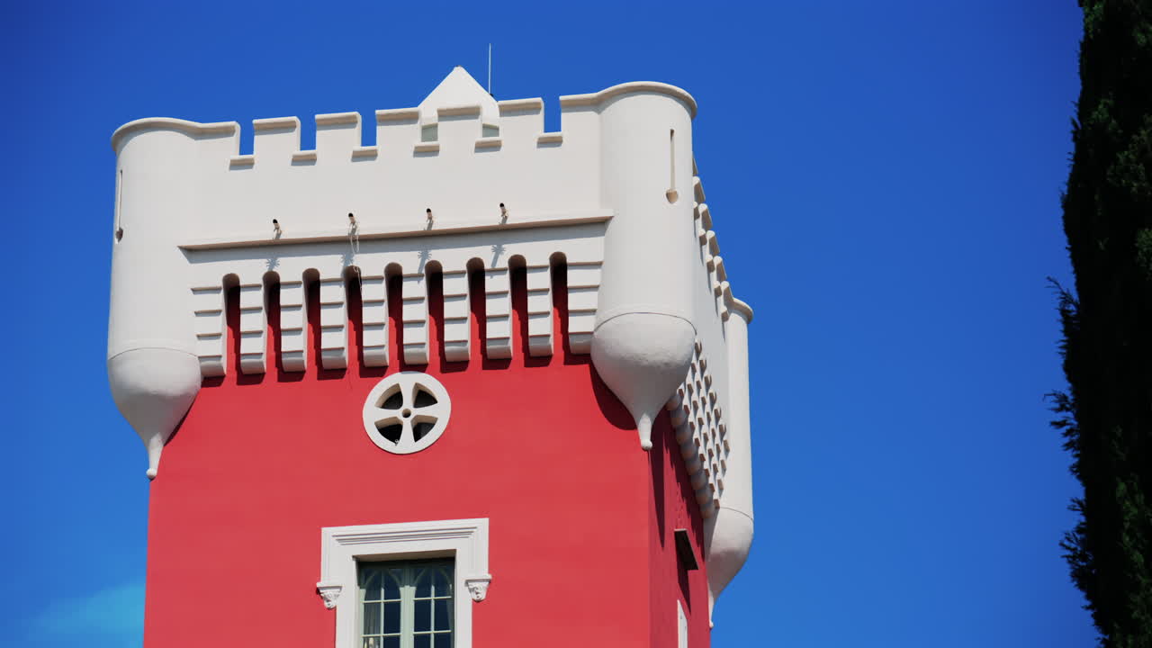 The red tower of the Cremat Castle Winery over the blue sky