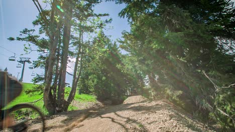 Ciclista-Salta-Por-Encima-De-La-Rampa-En-La-Cima-De-La-Colina-En-Kope,-Eslovenia-Con-Hermosos-Bosques-Y-Teleférico-En-El-Fondo