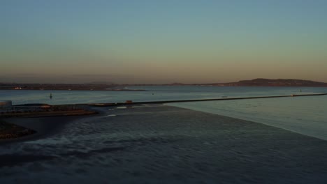 Aerial-over-Low-tide-during-twilight-at-great-south-wall-in-Dublin,-Ireland