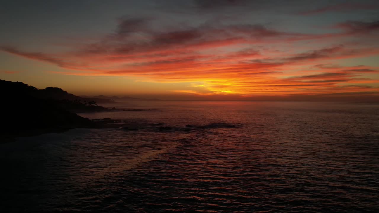 Drone hyperlapse of rolling ocean waves, glowing sunset over the sea