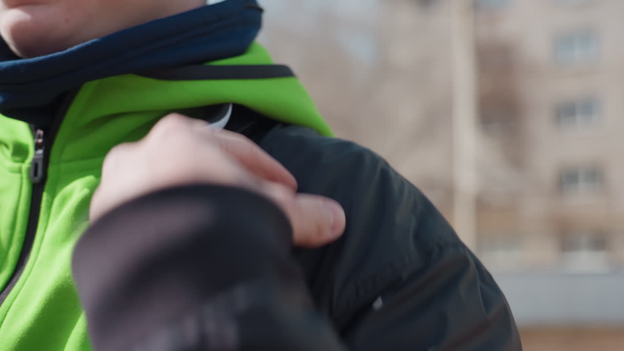 Tomar algo del bolsillo de la ropa, primer plano de una mano buscando en un bolsillo, persona que saca rápidamente un objeto del bolsillo de una sudadera con capucha, persona que mete rápidamente la mano en el bolsillo de su sudadera con capucha durante una sesión de entrenamiento al aire libre.