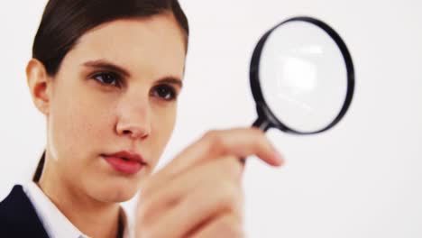 Close-up-of-businesswoman-looking-through-magnifying-glass