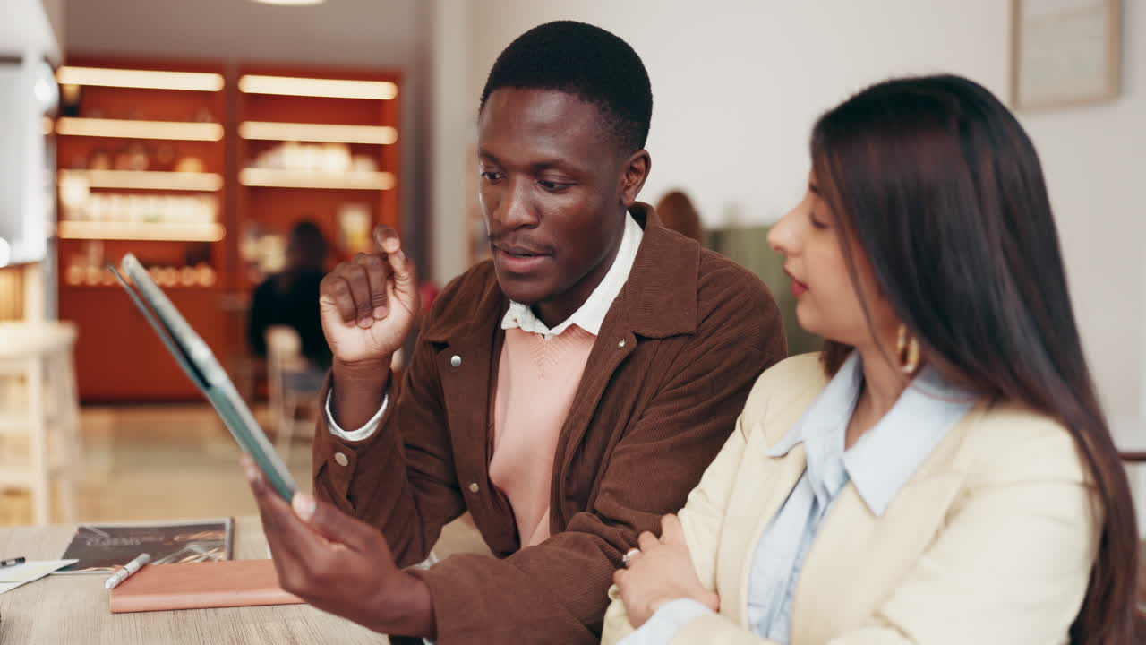 Two professionals collaborating with a tablet in a cafe