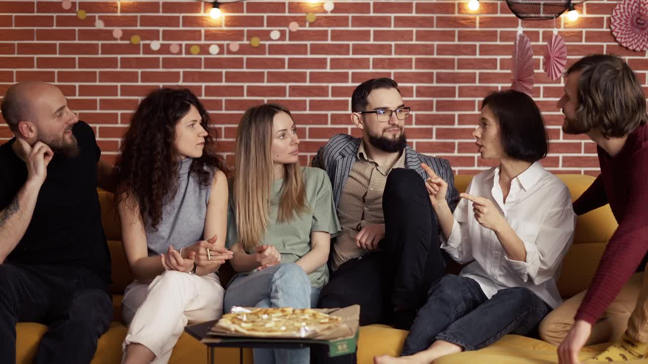 Amigos cercanos sentados en el sofá: charlando y comiendo pizza.