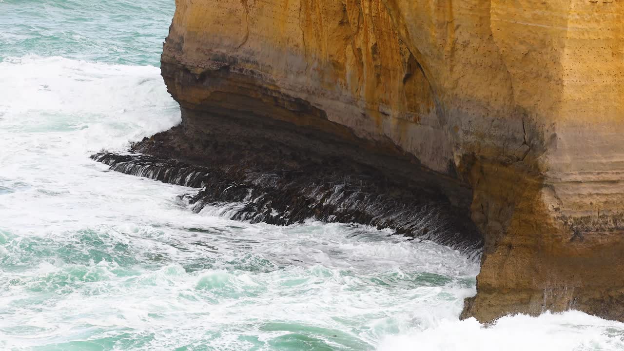Dynamic ocean waves crash against rugged cliffs under natural light at Port Campbell, creating a dramatic coastal scene